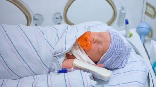 Ways to Care for Your Baby in the NICU, baby in isolette, orange pacifier